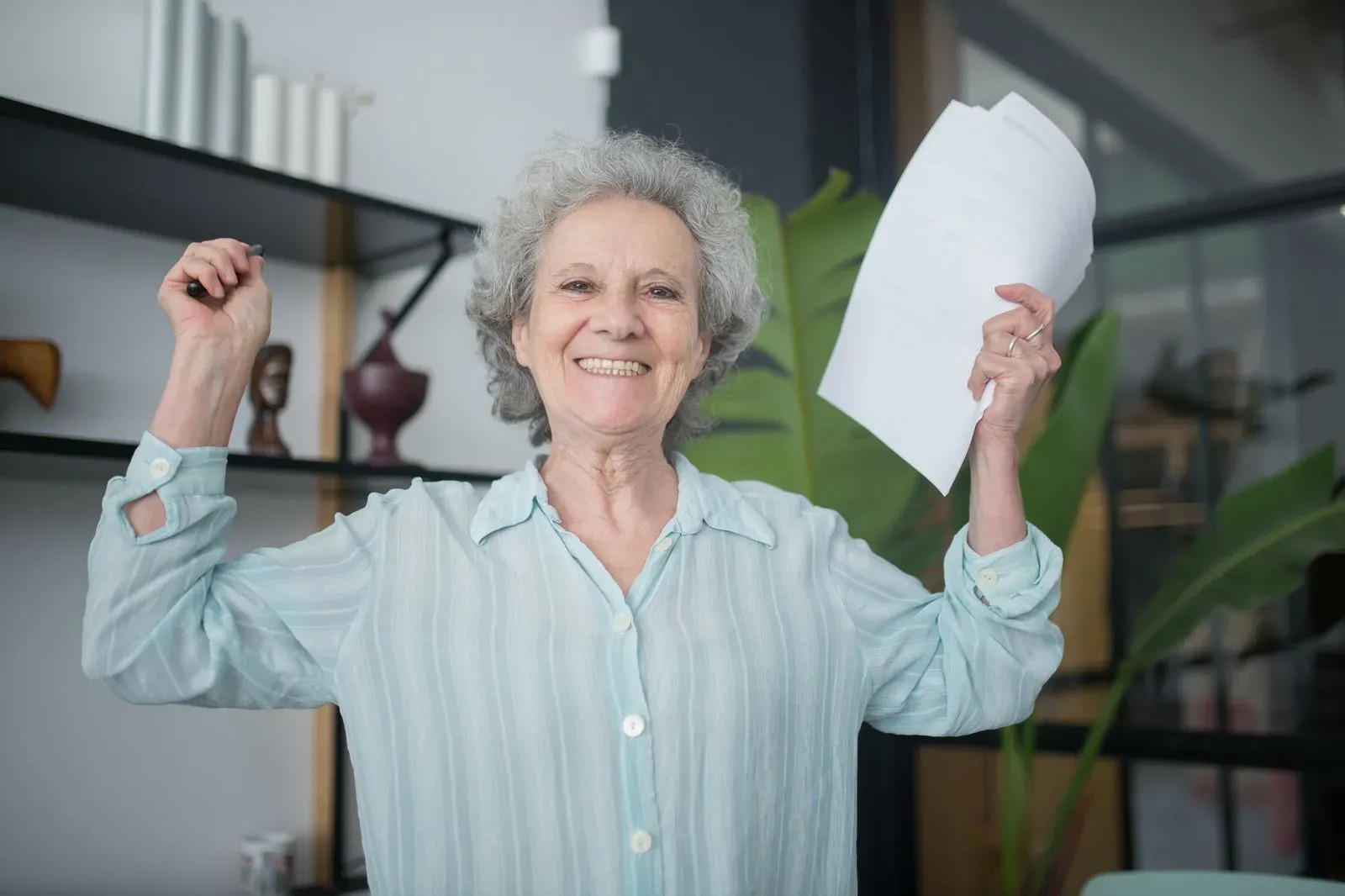 senior woman holding papers up happy